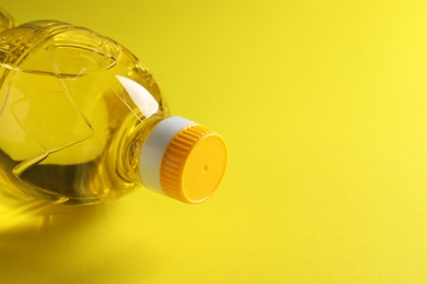 Photo of Plastic bottle of cooking oil on yellow background. Space for text