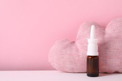 Photo of Cloud shaped pillow and nasal spray on color background, space for text