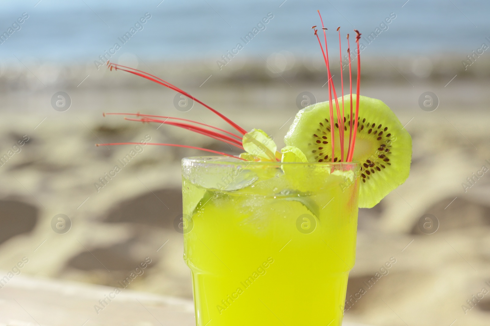 Photo of Glass of refreshing drink with kiwi and mint near sea, closeup