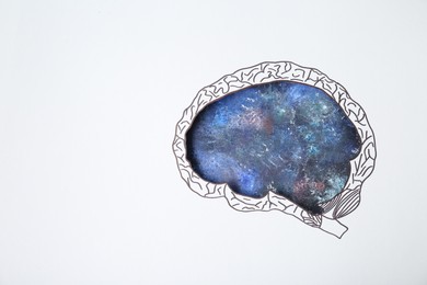 Photo of Imaginative thinking. Drawing of galaxy, top view through paper with brain shaped hole. Space for text