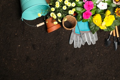 Photo of Flat lay composition with gardening tools and flowers on soil, space for text