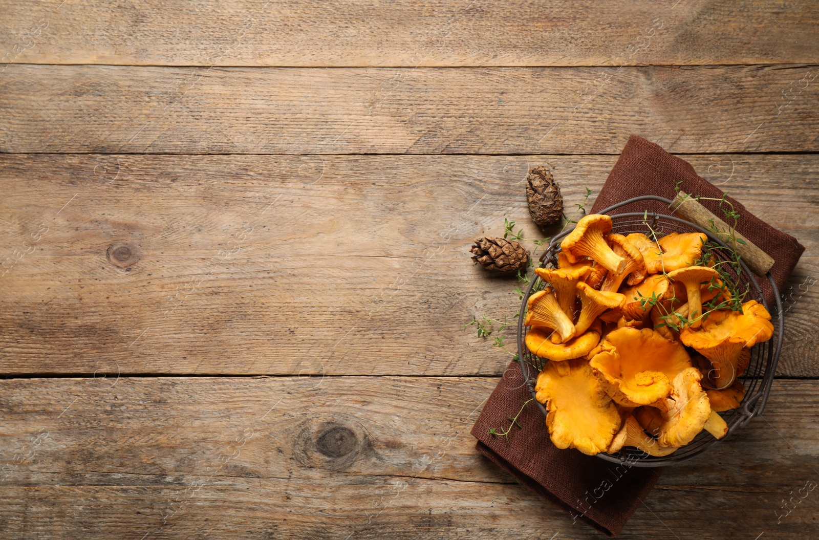 Photo of Fresh wild chanterelle mushrooms on wooden table, flat lay. Space for text