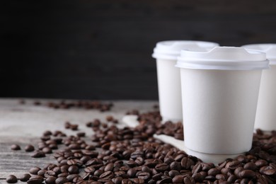 Photo of Coffee to go. Paper cups and roasted beans on table, closeup. Space for text
