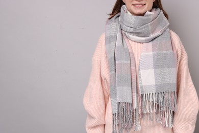 Photo of Woman in warm scarf on gray background, closeup. Space for text