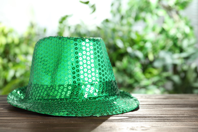 Photo of Green leprechaun hat on wooden table, space for text. St Patrick's Day celebration