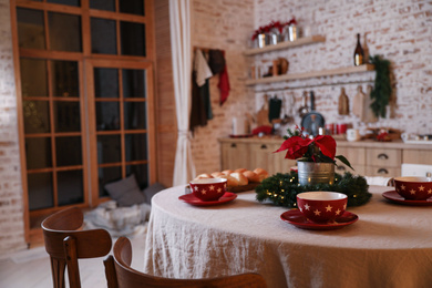 Photo of Dining table with red cups and mistletoe flower in kitchen