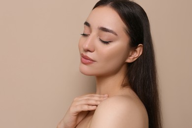 Photo of Portrait of beautiful young woman with elegant makeup on dark beige background. Space for text