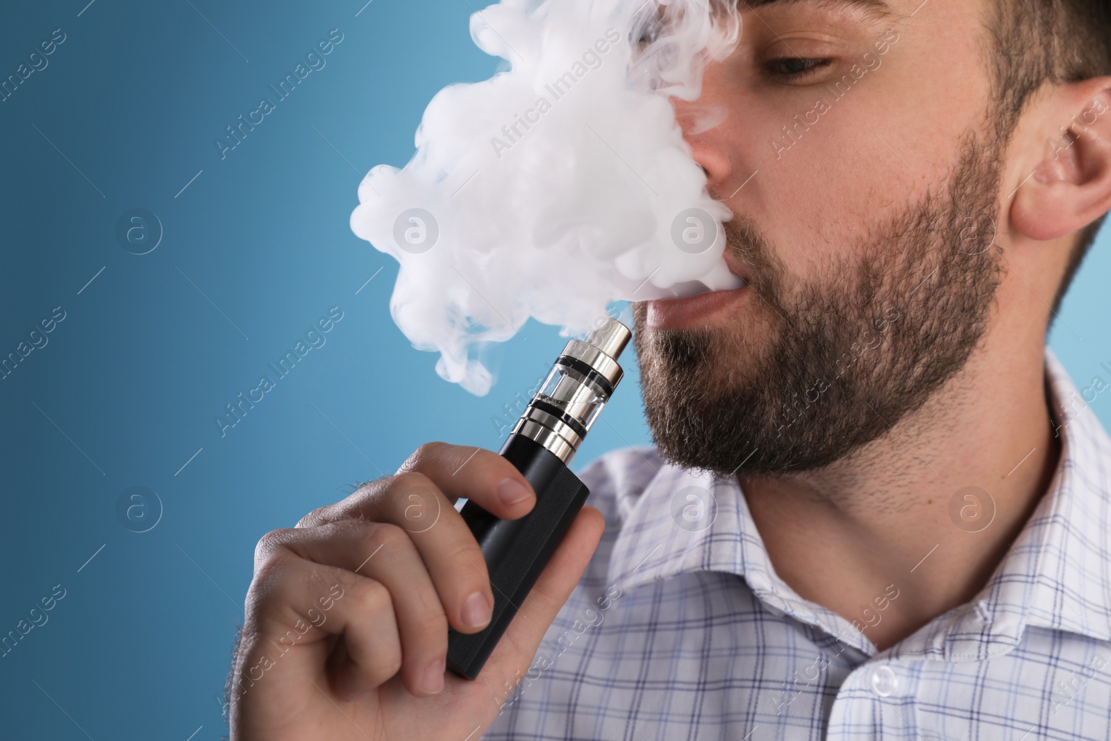 Photo of Man using electronic cigarette on light blue background, closeup