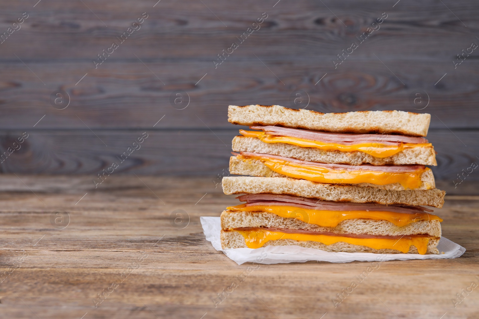 Delicious grilled sandwiches with ham and cheese on wooden table. Space for text Photo of Delicious grilled sandwiches with ham and cheese on wooden table. Space for text