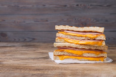 Photo of Delicious grilled sandwiches with ham and cheese on wooden table. Space for text