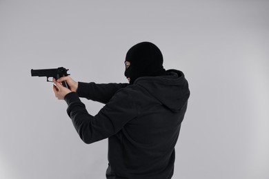 Photo of Man wearing black balaclava with gun on light grey background