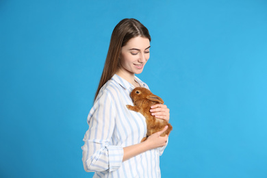 Photo of Young woman with adorable rabbit on blue background. Lovely pet