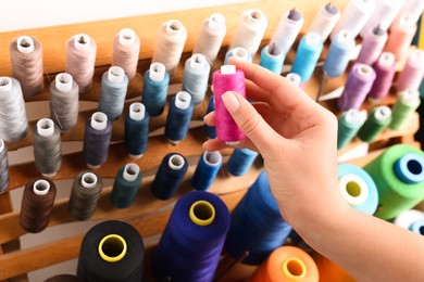Photo of Dressmaker taking pink thread from stand, closeup