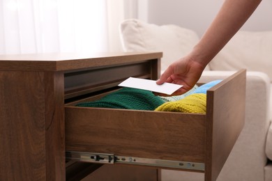 Photo of Woman putting scented sachet into drawer with clothes, closeup