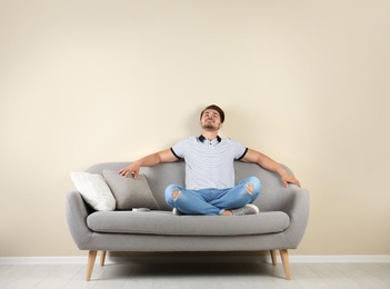Photo of Happy young man with air conditioner remote at home