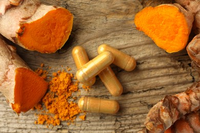 Photo of Aromatic turmeric powder, raw roots and pills on wooden surface, flat lay