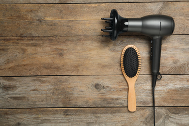 Photo of Hair dryer and brush on wooden table, flat lay with space for text. Professional hairdresser tool