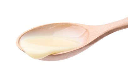 Photo of Wooden spoon with condensed milk isolated on white