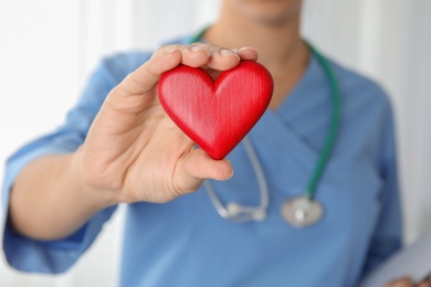 Photo of Doctor holding red heart in hand, closeup. Helping and supporting concept