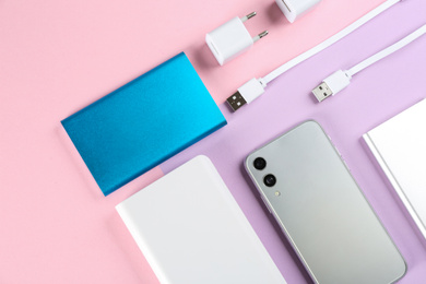 Photo of Mobile phone and portable chargers on color background, flat lay