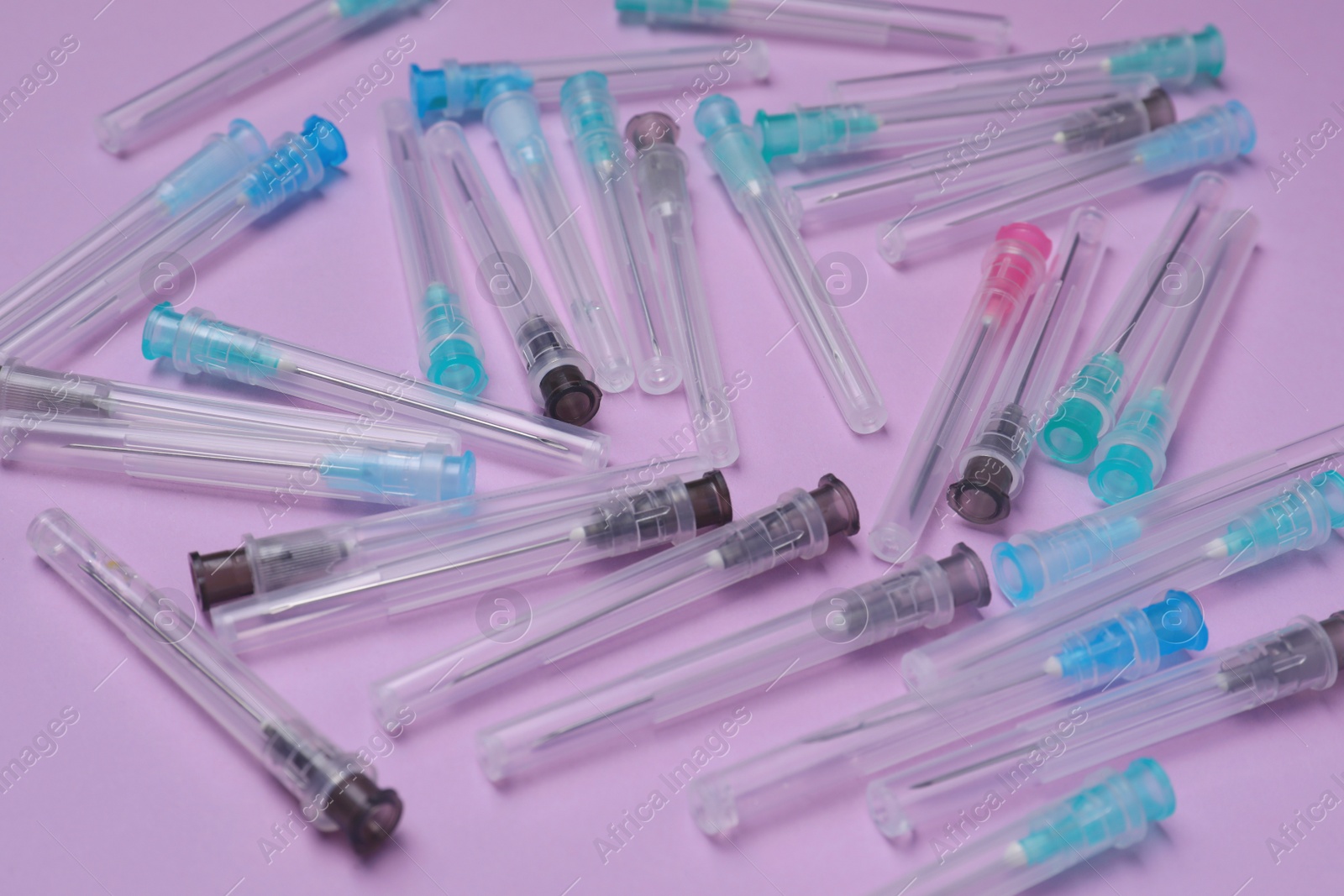 Photo of Many disposable syringe needles on violet background