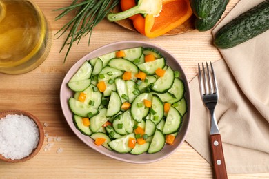 Photo of Tasty fresh salad with cucumber served on wooden table, flat lay