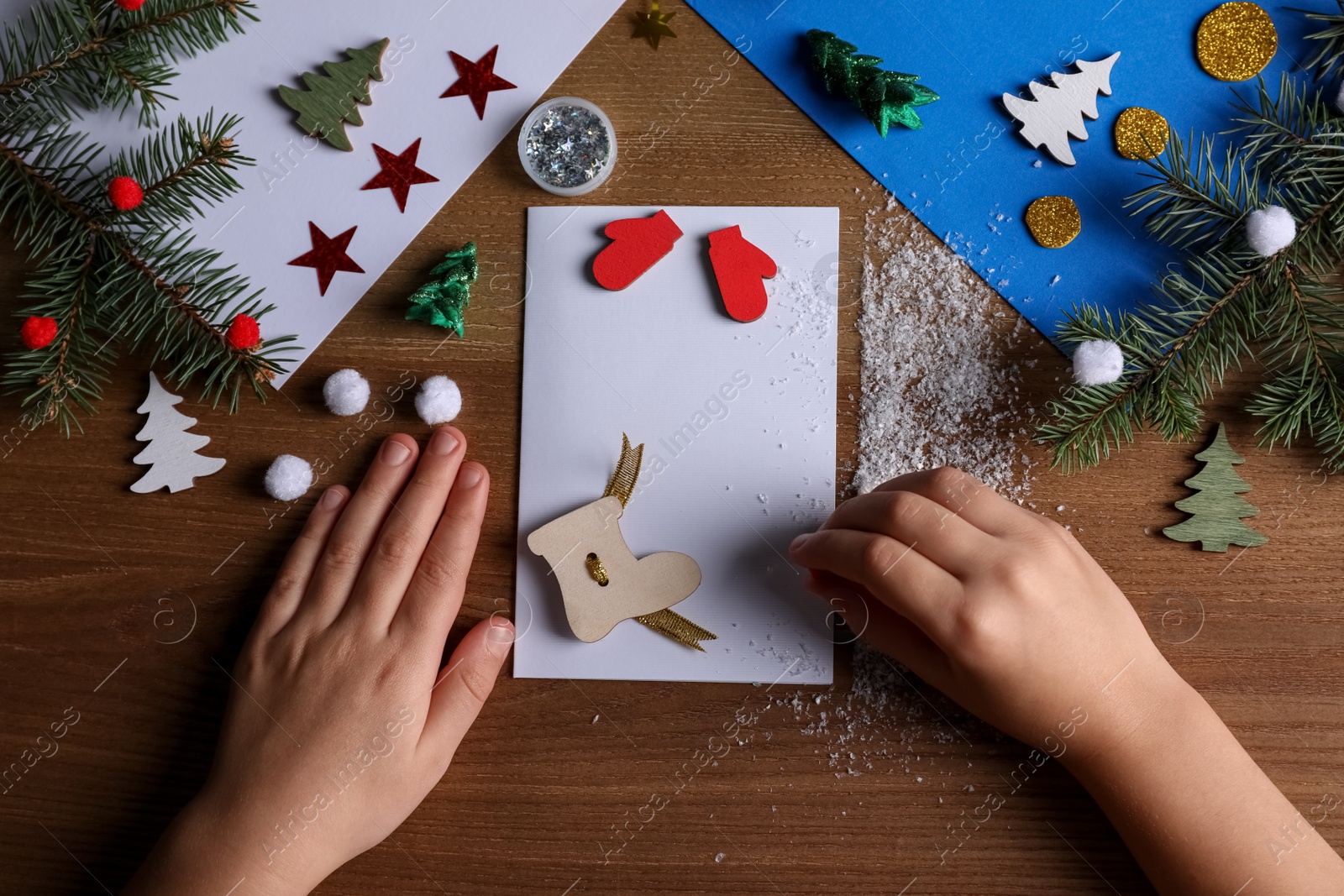 Photo of Little child making Christmas card at wooden table, top view