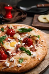 Photo of Pita pizza with prosciutto, pineapple, grilled tomatoes and egg on table, closeup