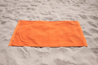 Photo of Beautiful soft orange beach towel on sand
