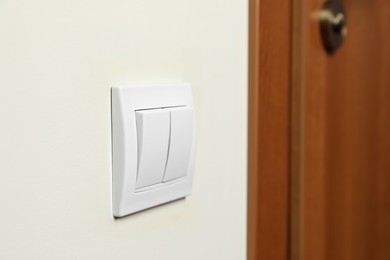 Photo of Modern plastic light switch on white wall indoors, closeup