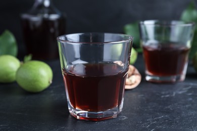 Photo of Delicious liqueur and fresh walnuts on black table