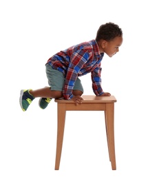 Photo of Little African-American boy climbing up stool on white background. Danger at home
