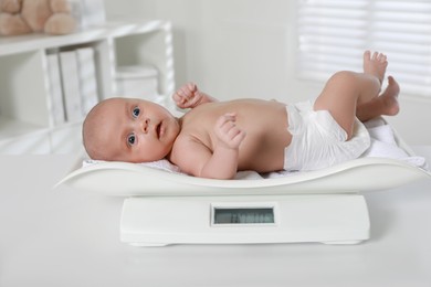 Photo of Cute little baby lying on scales in clinic