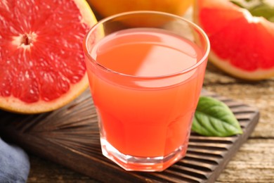 Photo of Glass of delicious grapefruit juice on wooden table, closeup