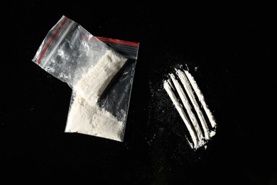 Photo of Drug addiction. Plastic bags with cocaine on black background, flat lay