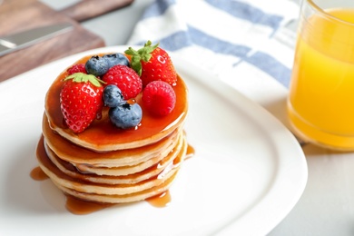 Photo of Tasty pancakes with berries and syrup on plate