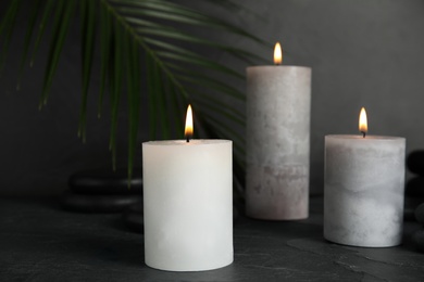 Photo of Burning candles and spa stones on black table