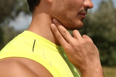 Photo of Young man checking pulse after training in park, closeup