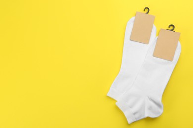 Photo of White cotton socks on yellow background, flat lay. Space for text