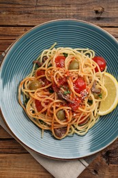 Photo of Delicious pasta with anchovies, tomatoes and parmesan cheese on wooden table, top view