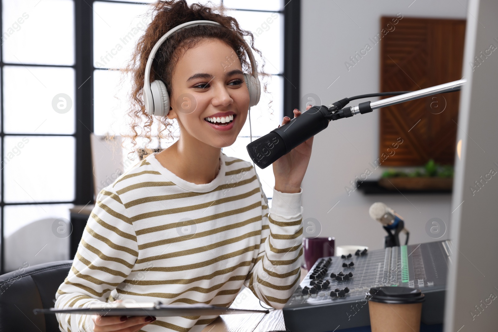 Photo of African American woman working as radio host in modern studio