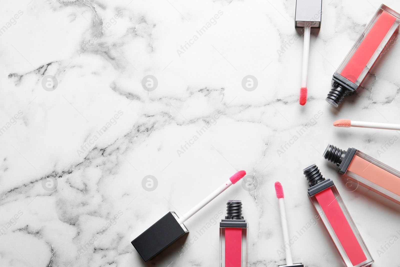 Photo of Liquid lipsticks on marble background, flat lay. Space for text