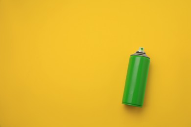 Can of green graffiti spray paint on yellow background, top view. Space for text