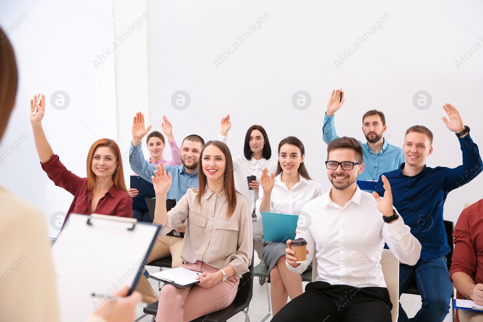 Photo of People raising hands to ask questions at business training indoors