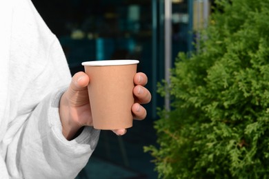 Photo of Woman holding cardboard cup of coffee outdoors, closeup. Space for text