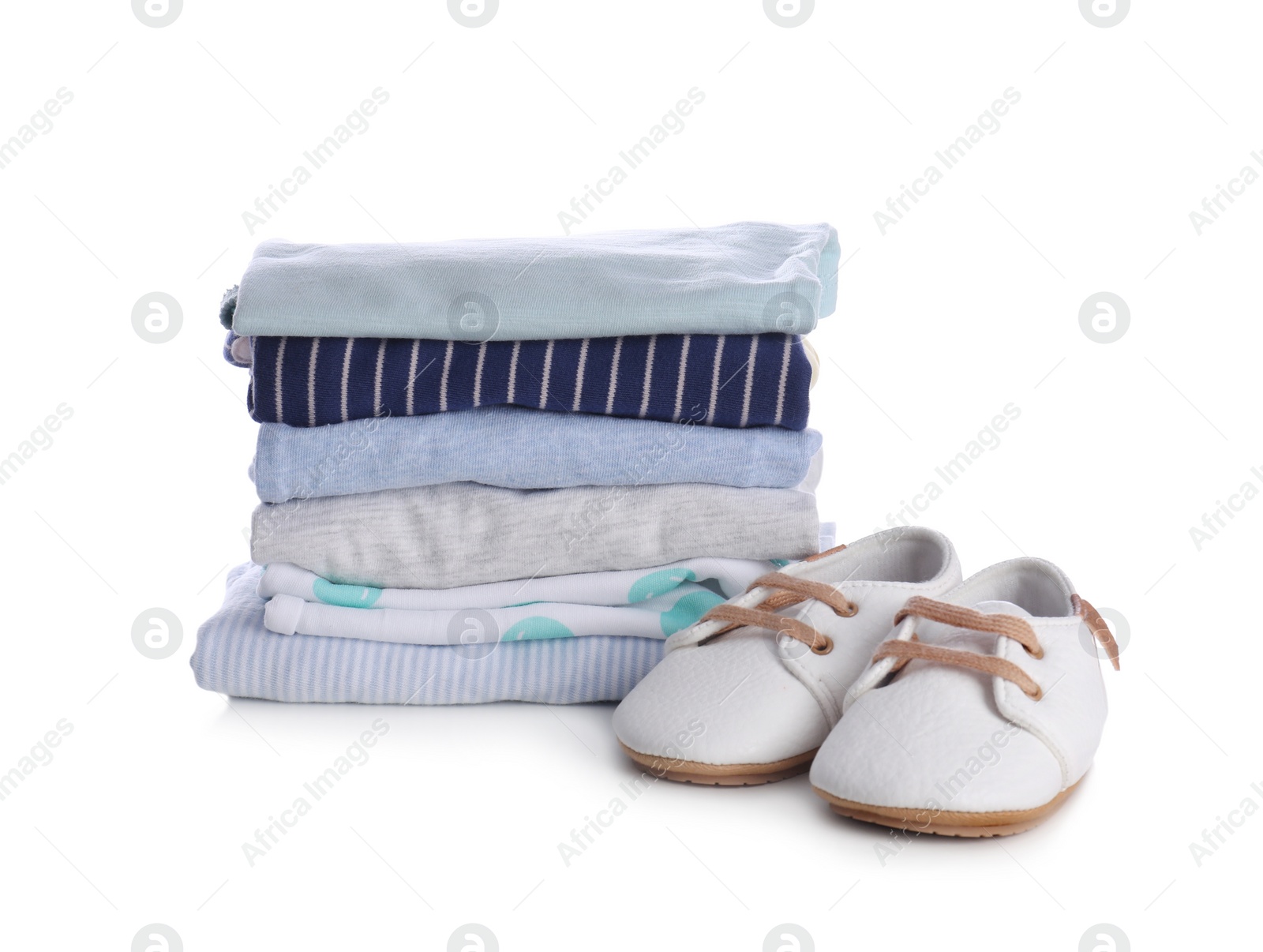 Photo of Stack of clean baby's clothes and small shoes on white background