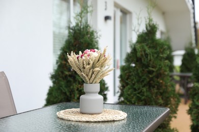 Photo of Beautiful bouquet of dry flowers in vase on glass table outdoors