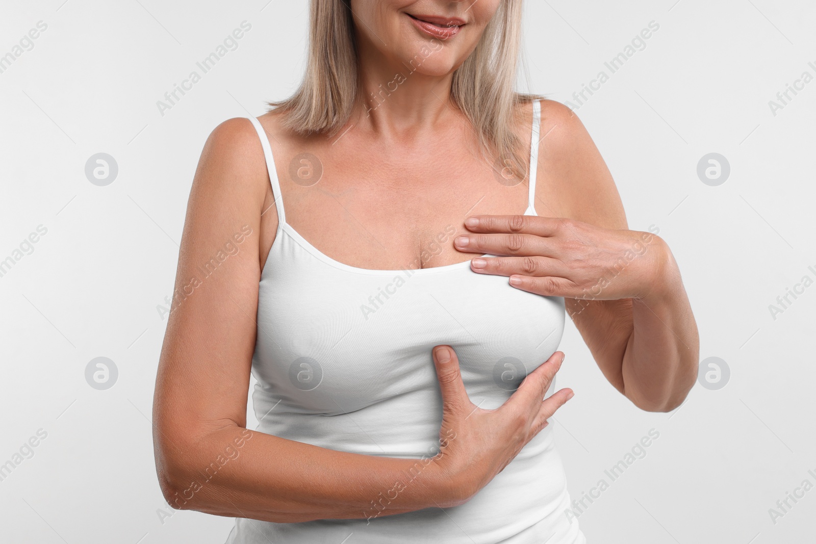 Photo of Woman doing breast self-examination on white background, closeup