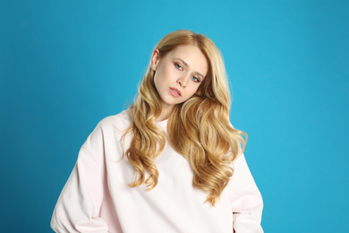 Portrait of beautiful young woman with dyed long hair on blue background