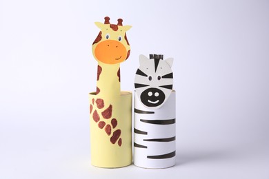 Photo of Toy giraffe and zebra made from toilet paper hubs on white background. Children's handmade ideas